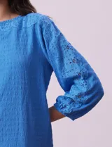 Blusa blanca texturada marca Ruby Rd, con escote redondo y mangas 3/4 con puño elastizado y apliques de broderie. Confeccionada en poliéster y elastano.
