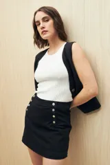 Minifalda de jean azul oscuro con botones metálicos plateados en el frente.