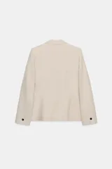 Blazer color beige de cuello solapa y manga larga. Tiene bolsillos con solapa en el delantero y cierre frontal con un botón.