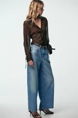 Pantalón de jean celeste de tiro alto, corte wide leg cropped, con cinco bolsillos y cinturón marrón con tachas.