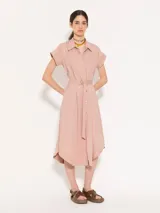 Vestido camisero midi color rosa, de corte recto, con cuello camisero, mangas cortas con puños, cinturón con hebilla forrada, cierre frontal con botones a tono y bolsillos plaqué en el pecho.