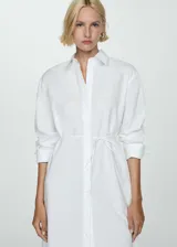 Camisa larga blanca de popelina de algodón y lyocell, con cuello camisero, cierre frontal con botones y lazo a la cintura.