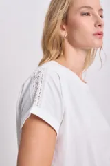 Remera blanca de manga corta con detalle de puntilla en el cuello y las mangas.