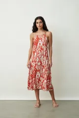 Vestido midi con estampado abstracto en tonos naranja y blanco, breteles finos y corte evasé.