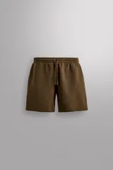 Bermuda jogger color marrón confeccionada en tejido de algodón con interior rizo. Cuenta con cintura elástica ajustable con cordón y bolsillos laterales en la cadera.