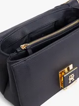 Cartera de lona color beige con rayas verticales azul marino y plateada. Tiene asa superior y correa extraíble y ajustable. El cierre es con solapa magnética y tiene el logo de Tommy Hilfiger en dorado.