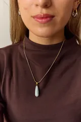 Collar dorado con cadena fina y dije colgante en forma de lágrima de piedra natural azul con vetas blancas.