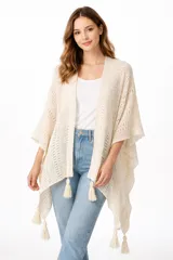 Poncho color beige de tejido de punto calado, con mangas amplias y flecos decorativos en el dobladillo.