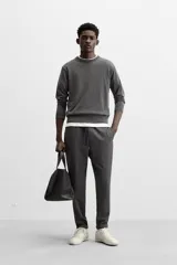 Pantalón negro de corte cropped, con cintura elástica ajustable con cordón, bolsillos laterales y traseros de vivo. El bajo tiene terminación con vuelta.