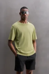 Remera verde oliva de corte relaxed fit, cuello redondo y manga corta. Tiene un pequeño logo estampado en el bajo.