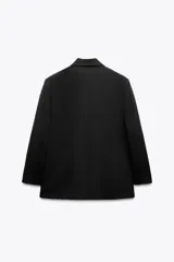 Blazer negra oversize con cuello solapa, manga larga con hombreras y bolsillos delanteros con solapa. Cierre frontal cruzado con botones.