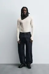 Camiseta de manga larga color crudo, corte ajustado y cuello redondo. Tiene aberturas en los puños y efecto lavado.