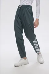 Pantalón de jogging color celeste con cintura elástica ajustable con cordón y puños elásticos. Presenta tres tiras verticales blancas en la parte inferior de la pierna.