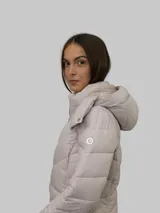Campera puffer color beige con cierre frontal y bolsillos laterales con cierre. Tiene capucha desmontable y relleno acolchado.
