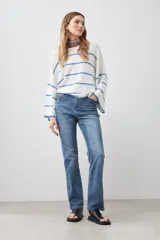 Sweater de punto color blanco con rayas horizontales azules, de corte holgado y mangas largas acampanadas.