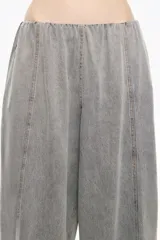 Pantalón de denim gris lavado, tiro bajo, de corte ancho y holgado. Presenta pespuntes a contraste en color marrón claro a lo largo de las costuras.