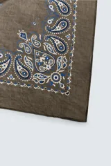 Pañuelo bandana color verde oliva con estampado paisley en azul y blanco.