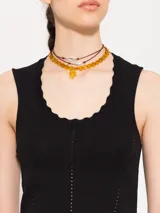 Top negro de hilado frío, corte ajustado y largo hasta la primera cadera. Sin mangas, con cuello redondeado y profundo.