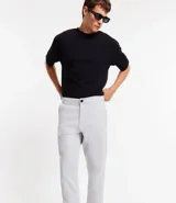 Pantalón de hombre color gris claro, corte slim, confeccionado en sarga leve. Cuenta con cierre de botón y cremallera, y bolsillos.