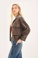 Campera marrón de lino con cierre frontal y bolsillos con solapa. Tiene mangas largas con presilla interna para arremangar.