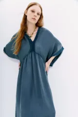 Vestido al tobillo color negro, de calce amplio y mangas al codo. Tiene apliques de gasa en escote y mangas, y recortes con frunce en la cintura.