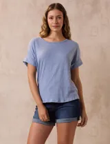 Remera celeste de corte recto, con cuello redondo y mangas cortas con dobladillo. Presenta detalle de botones en la espalda.