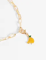 Dije con forma de banana esmaltada en color amarillo con detalles en verde, enganchado a un aro dorado.