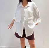 Camisa oversize rosada de lino, con cuello clásico, cierre frontal con botones, dos bolsillos de parche en el pecho y mangas largas con puños abotonados.
