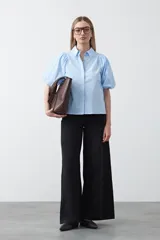 Camisa blanca de algodón con cuello camisero y mangas cortas abullonadas. Presenta un corte relajado y cierre frontal de botones.