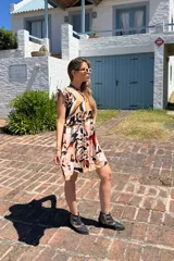 Vestido corto con estampado abstracto en tonos rosa, beige, negro y rojo. Tiene escote cuadrado, breteles anchos con volados y corte holgado.