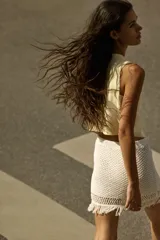 Chaleco color crema con cuello redondo y cierre frontal con botones metálicos.