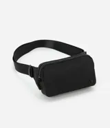 Riñonera negra con cierre de cremallera, correa ajustable y logo de la marca en relieve. Fabricada con poliéster reciclado.