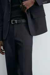 Pantalón de vestir negro de corte relaxed fit confeccionado en tejido con lana. Cuenta con bolsillos frontales y traseros de doble vivo con botón. Cierre frontal con cremallera y botón.