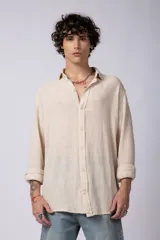 Camisa blanca de lino con cuello clásico, manga larga con puños abotonados y corte holgado. 