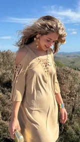 Vestido corto color beige, con escote en V con cordones, mangas 3/4 acampanadas con cordones y hombros descubiertos.