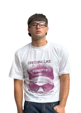 Remera blanca de algodón con cuello redondo y estampado frontal con una gorra y lentes de sol en color violeta.