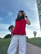 Blusa roja sin mangas con escote con lazo y detalle de volados en el ruedo.