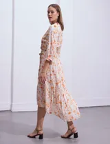 Vestido midi estampado con flores y mandalas en tonos naranja, rojo y celeste, con escote en V, mangas 3/4 con puños fruncidos, cintura elastizada con lazo y ruedo irregular.