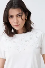 Remera color crudo de algodón, de corte recto y manga corta, con bordados calados en el escote.