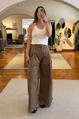 Pantalón marrón de corte ancho con pinzas en la cintura y bolsillos laterales.