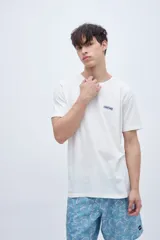 Remera de manga corta color lila con cuello redondo y parche con texto en el pecho.