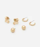 Set de tres pares de aros dorados: un par con forma de flor, un par de aros tipo argolla trenzada y un par de aros tipo bolita.