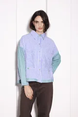 Camisa corta con cuerpo a rayas verticales azules y blancas, mangas a rayas verticales verdes y blancas, cuello camisero y cierre frontal con botones dorados.