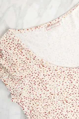 Remera blanca con estampado de lunares marrones, corte al cuerpo y mangas cortas.
