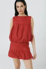 Top musculosa de lino color rojo, con cuello redondo y diseño estilo balloon con volumen en el ruedo. Cuenta con cierre de botones en la parte trasera.