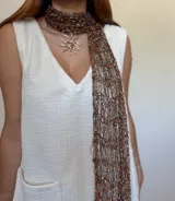 Bufanda tejida artesanalmente con hilado fantasía en tonos marrón, naranja y blanco.