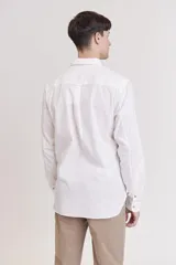 Camisa blanca de manga larga con cuello abotonado.