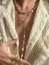 Set de dos collares dorados: uno tipo choker con esferas y otro tipo corbatín con dije de cadena con piedras de colores.