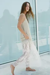 Vestido largo color beige, de punto fino, con escote en V y tirantes finos. La parte inferior es de encaje blanco.