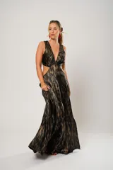 Vestido largo de fiesta con estampado abstracto en tonos dorados y negros. Tiene escote en V, corte en la cintura y aberturas laterales.